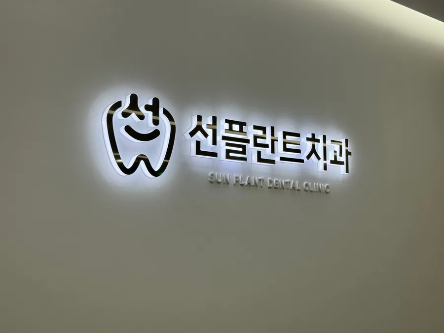 흰 벽에 조명을 받은 선플란트치과 로고 간판